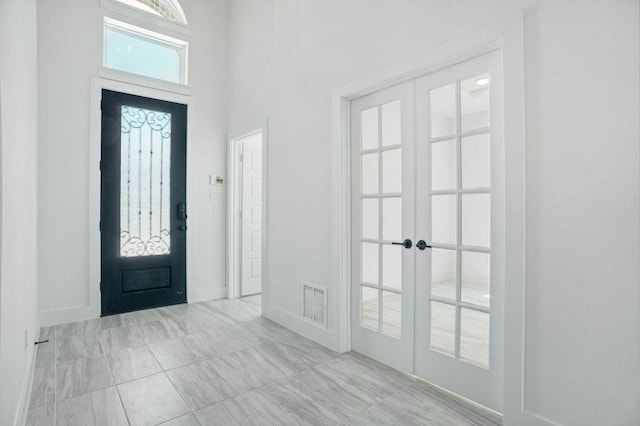 entryway featuring a towering ceiling and french doors