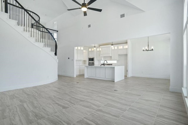 unfurnished living room with ceiling fan with notable chandelier, sink, and high vaulted ceiling