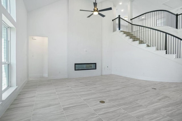 unfurnished living room featuring a towering ceiling and ceiling fan