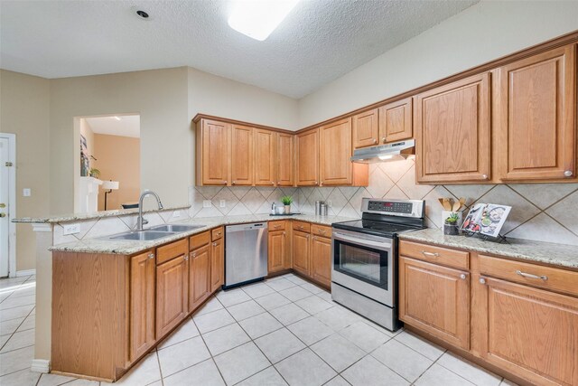 kitchen featuring backsplash, light tile patterned flooring, light stone countertops, and stainless steel appliances