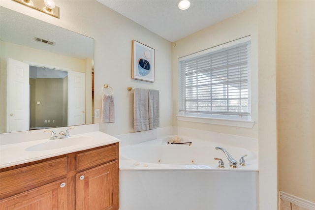 bathroom with vanity, a textured ceiling, and a tub