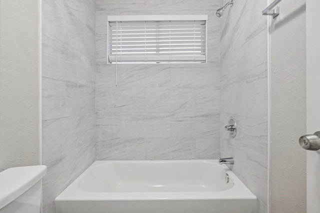 bathroom with tiled shower / bath and toilet