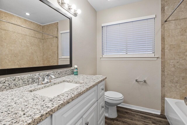 full bathroom with vanity, hardwood / wood-style floors, tiled shower / bath, and toilet