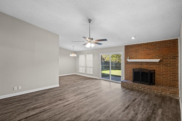 unfurnished living room featuring a brick fireplace, dark wood-type flooring, ceiling fan with notable chandelier, and a textured ceiling