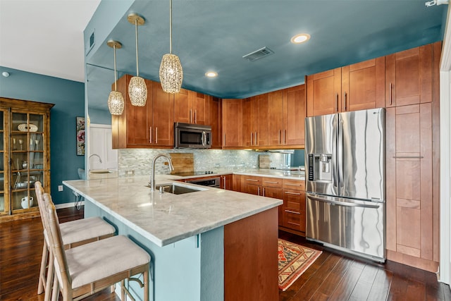 kitchen with sink, stainless steel appliances, dark hardwood / wood-style flooring, kitchen peninsula, and pendant lighting