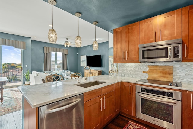 kitchen with stainless steel appliances, kitchen peninsula, sink, and hanging light fixtures