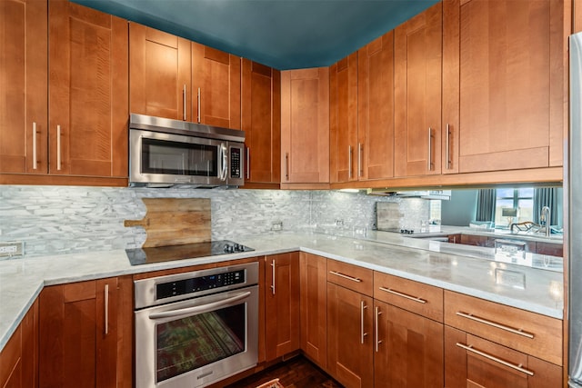 kitchen featuring dark hardwood / wood-style flooring, light stone counters, appliances with stainless steel finishes, and tasteful backsplash