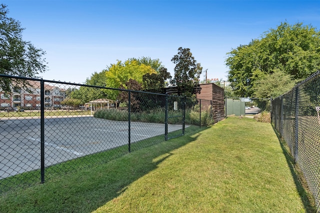 view of tennis court featuring a lawn