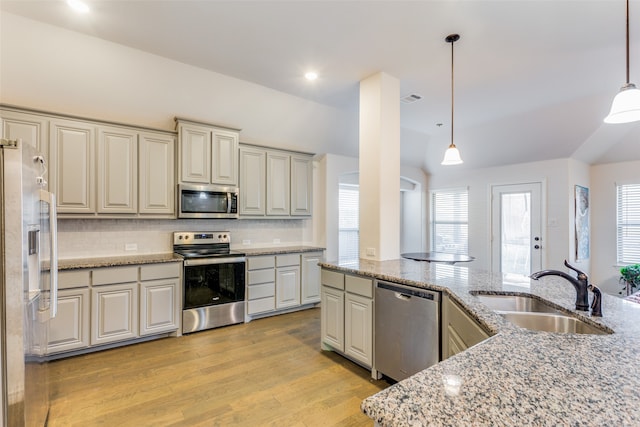 kitchen with sink, tasteful backsplash, light hardwood / wood-style floors, decorative light fixtures, and appliances with stainless steel finishes