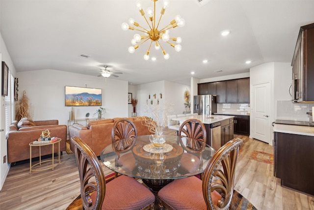 dining area with lofted ceiling, ceiling fan with notable chandelier, and light wood-type flooring