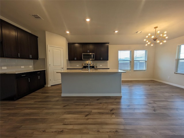 kitchen with dark brown cabinetry, an island with sink, sink, and dark hardwood / wood-style flooring