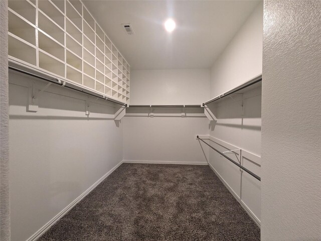 walk in closet featuring dark colored carpet