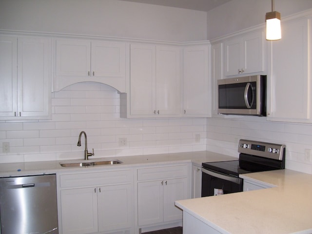 kitchen with hanging light fixtures, white cabinetry, sink, and stainless steel appliances