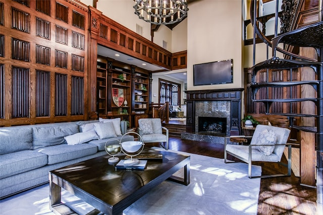 living room with hardwood / wood-style floors, a fireplace, a high ceiling, and an inviting chandelier