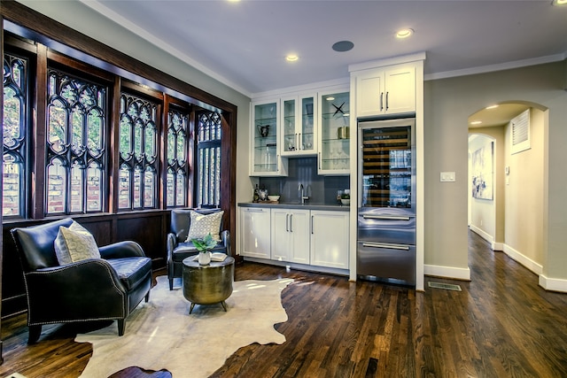 bar with ornamental molding, white cabinetry, beverage cooler, and dark wood-type flooring