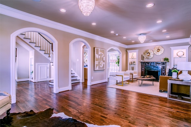 living room featuring a premium fireplace, an inviting chandelier, dark hardwood / wood-style floors, and ornamental molding