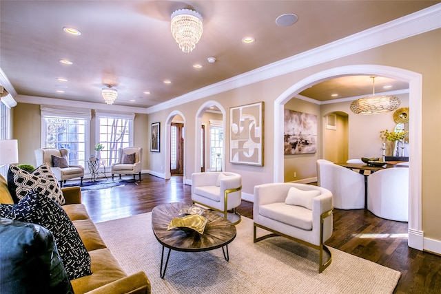 living room with ornamental molding, dark wood-type flooring, and an inviting chandelier