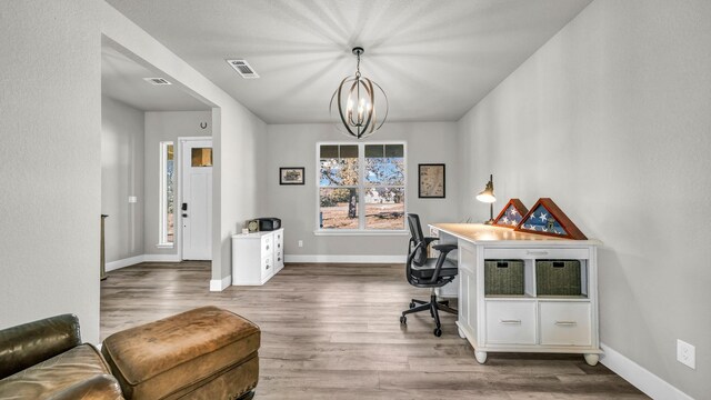 home office with a chandelier and light hardwood / wood-style flooring