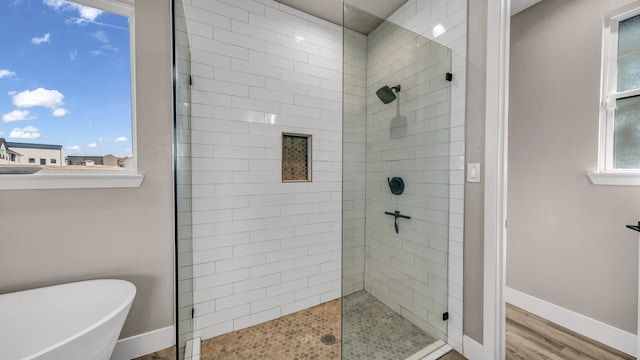 bathroom featuring wood-type flooring and shower with separate bathtub