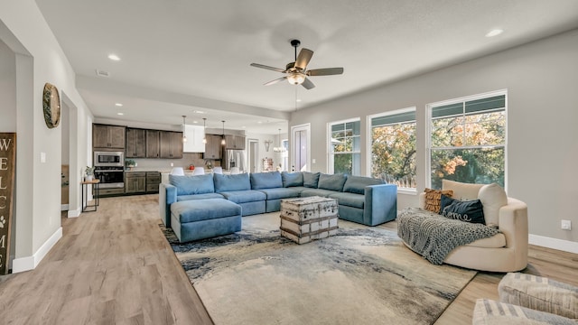 living room featuring ceiling fan and light hardwood / wood-style floors