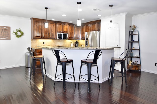 kitchen with stainless steel appliances, decorative light fixtures, a kitchen breakfast bar, and light stone counters