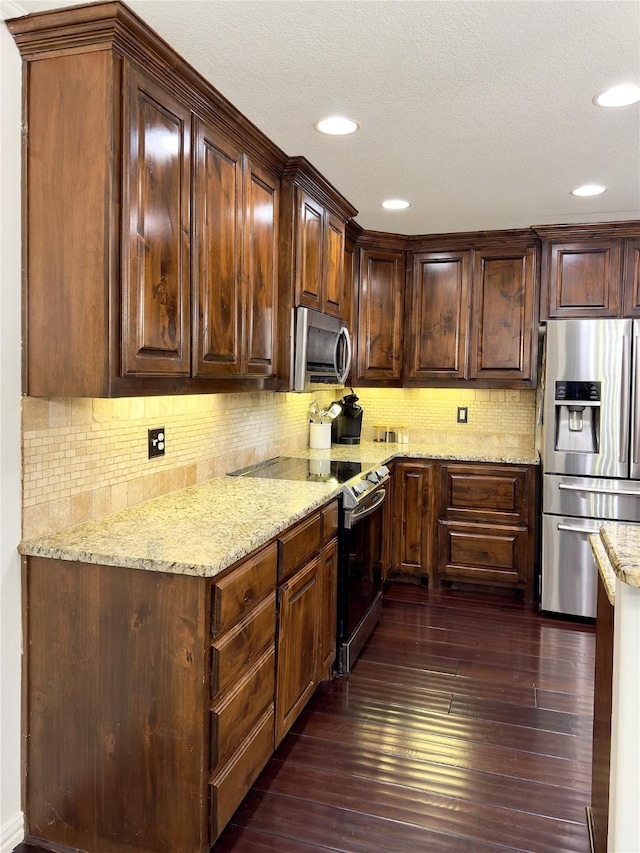 kitchen featuring dark wood-type flooring, light stone countertops, stainless steel appliances, backsplash, and dark brown cabinets