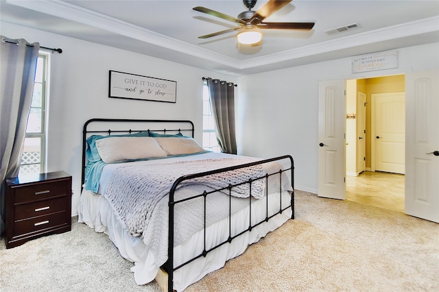 bedroom featuring ceiling fan, light colored carpet, crown molding, and a tray ceiling