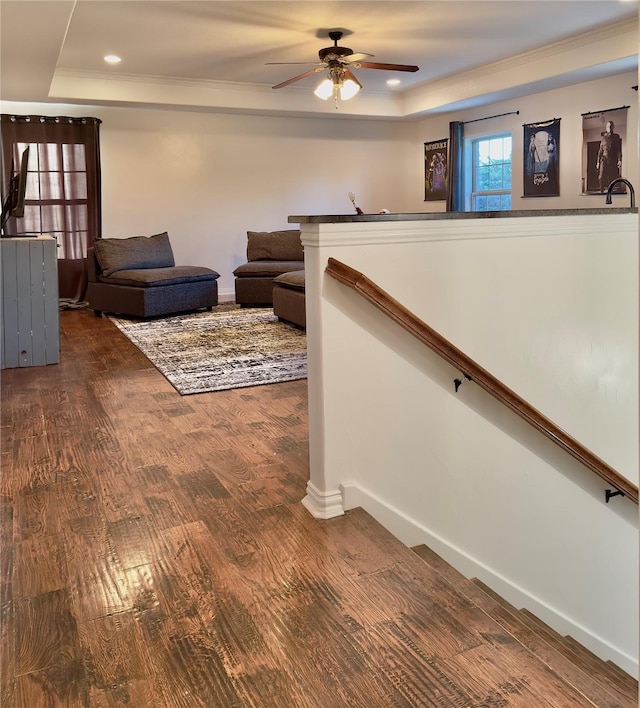 living room featuring hardwood / wood-style flooring, ceiling fan, a tray ceiling, and ornamental molding