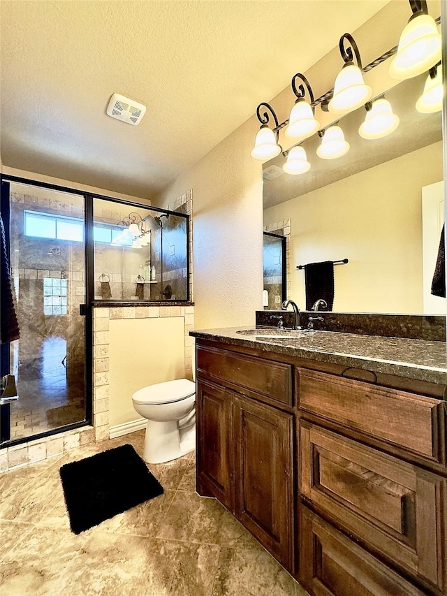 bathroom featuring toilet, a textured ceiling, walk in shower, and vanity