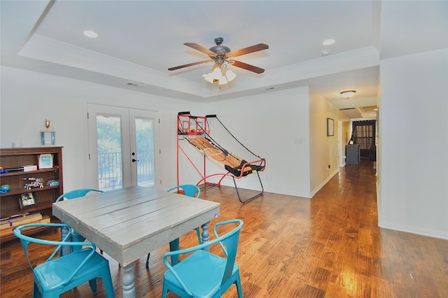 dining area featuring hardwood / wood-style floors, a raised ceiling, ceiling fan, ornamental molding, and french doors