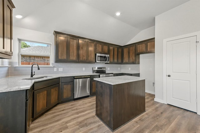 kitchen featuring lofted ceiling, appliances with stainless steel finishes, dark brown cabinets, light wood-style floors, and a sink