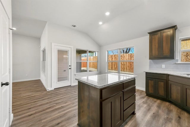 kitchen with visible vents, vaulted ceiling, backsplash, and wood finished floors