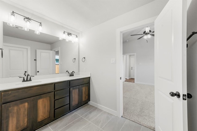 bathroom featuring tile patterned flooring, a sink, baseboards, and double vanity