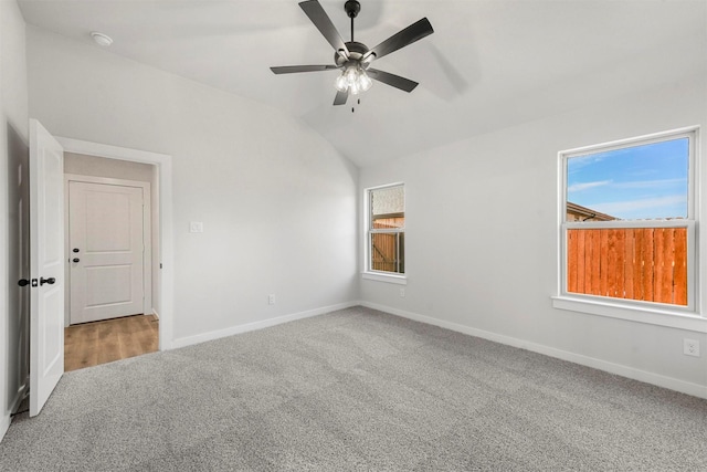 carpeted spare room featuring a ceiling fan, lofted ceiling, and baseboards