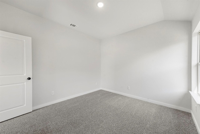 unfurnished room featuring lofted ceiling, carpet, visible vents, and baseboards