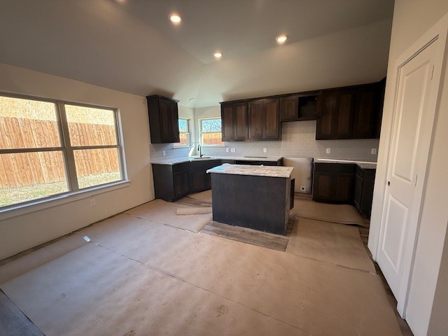 kitchen with tasteful backsplash, a kitchen island, lofted ceiling, and dark brown cabinetry