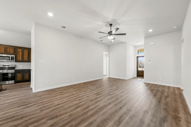 unfurnished living room with ceiling fan, wood finished floors, visible vents, and baseboards