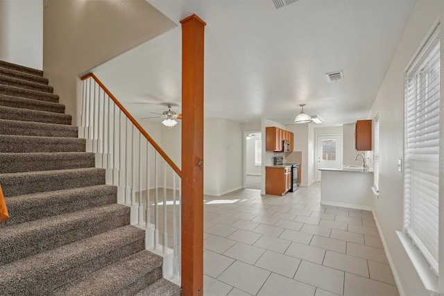 stairs with tile patterned flooring, sink, and ceiling fan