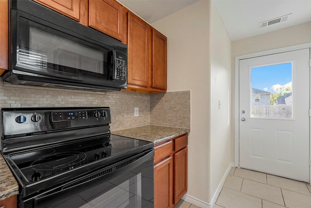 kitchen with light stone countertops, decorative backsplash, black appliances, and light tile patterned floors