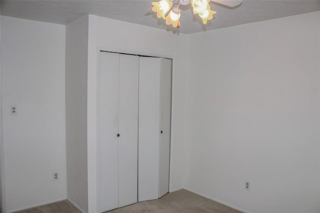 unfurnished bedroom featuring ceiling fan, a closet, and light colored carpet