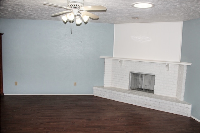 unfurnished living room with dark hardwood / wood-style floors, ceiling fan, a textured ceiling, and a brick fireplace