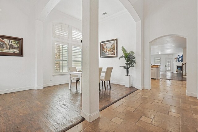 unfurnished dining area with hardwood / wood-style flooring, crown molding, and a high ceiling