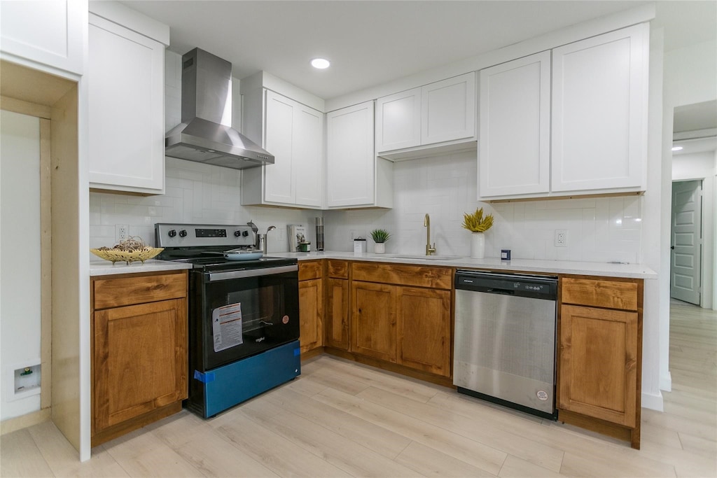 kitchen featuring dishwasher, sink, wall chimney exhaust hood, light wood-type flooring, and black range with electric cooktop