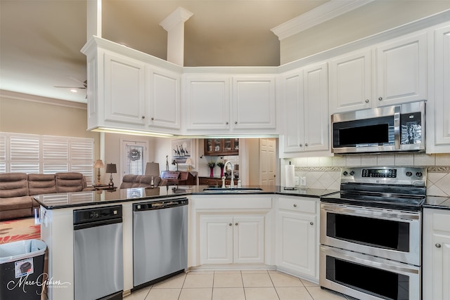 kitchen with sink, white cabinetry, ornamental molding, appliances with stainless steel finishes, and kitchen peninsula