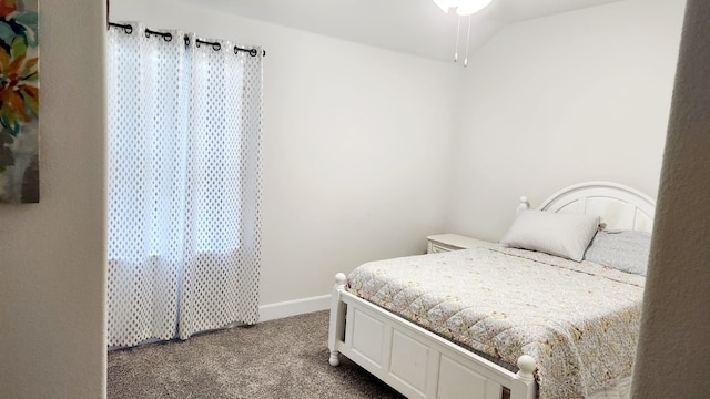 bedroom with vaulted ceiling, dark carpet, and multiple windows