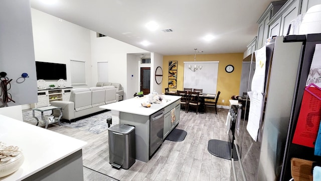 kitchen featuring gray cabinetry, a kitchen island, light wood-type flooring, and a chandelier