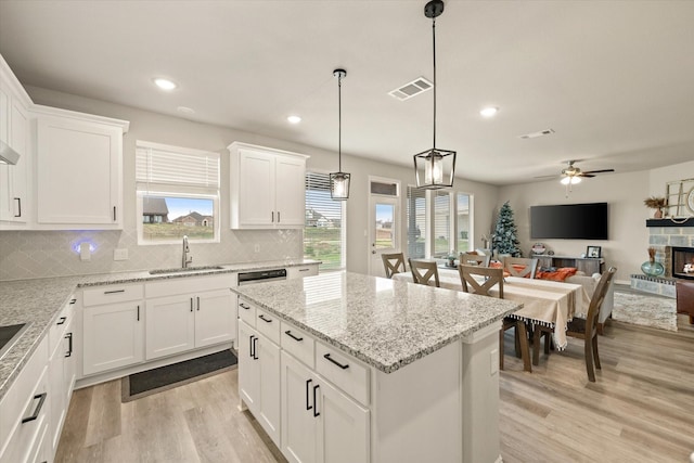 kitchen with white cabinets, ceiling fan, pendant lighting, a kitchen island, and sink