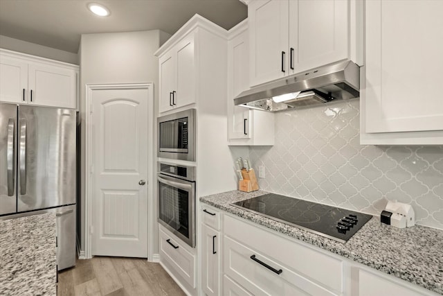 kitchen with appliances with stainless steel finishes, light hardwood / wood-style flooring, white cabinets, and decorative backsplash