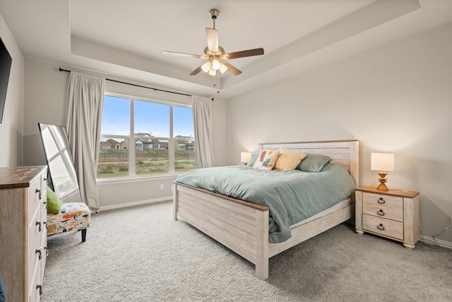 bedroom featuring light colored carpet, ceiling fan, and a tray ceiling