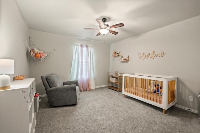 carpeted bedroom with a crib and ceiling fan